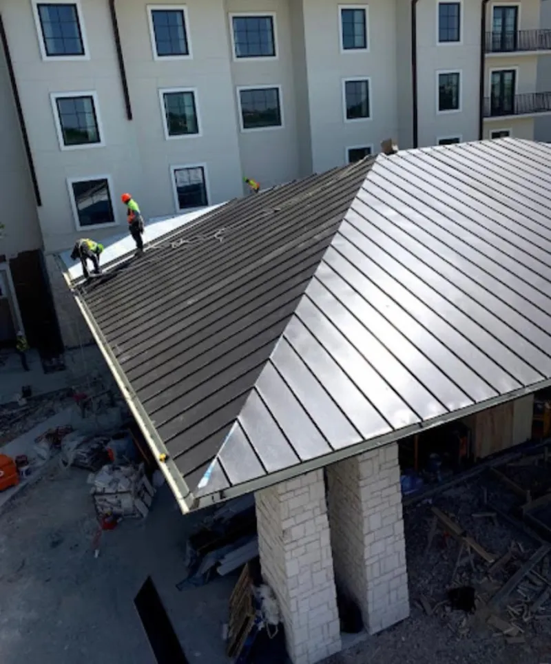 Crew installing standing seam metal roof panels on a commercial project in Waxhaw